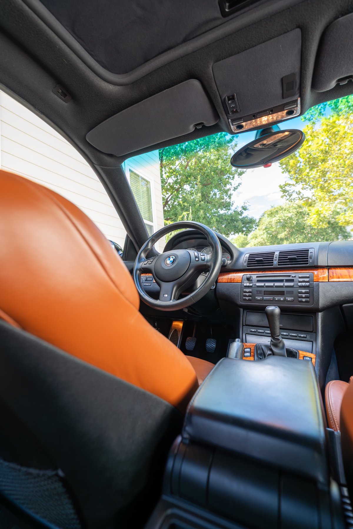 Interior view of a 2002 BMW M3 with tan leather seats, wood trim, and a manual transmission.