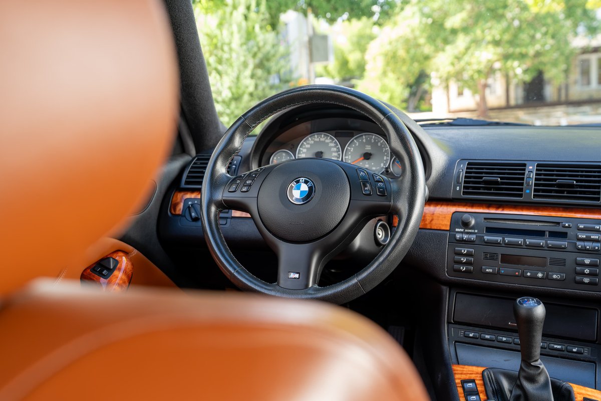 2002 BMW M3 interior, showing leather seats, wood trim, and M steering wheel.