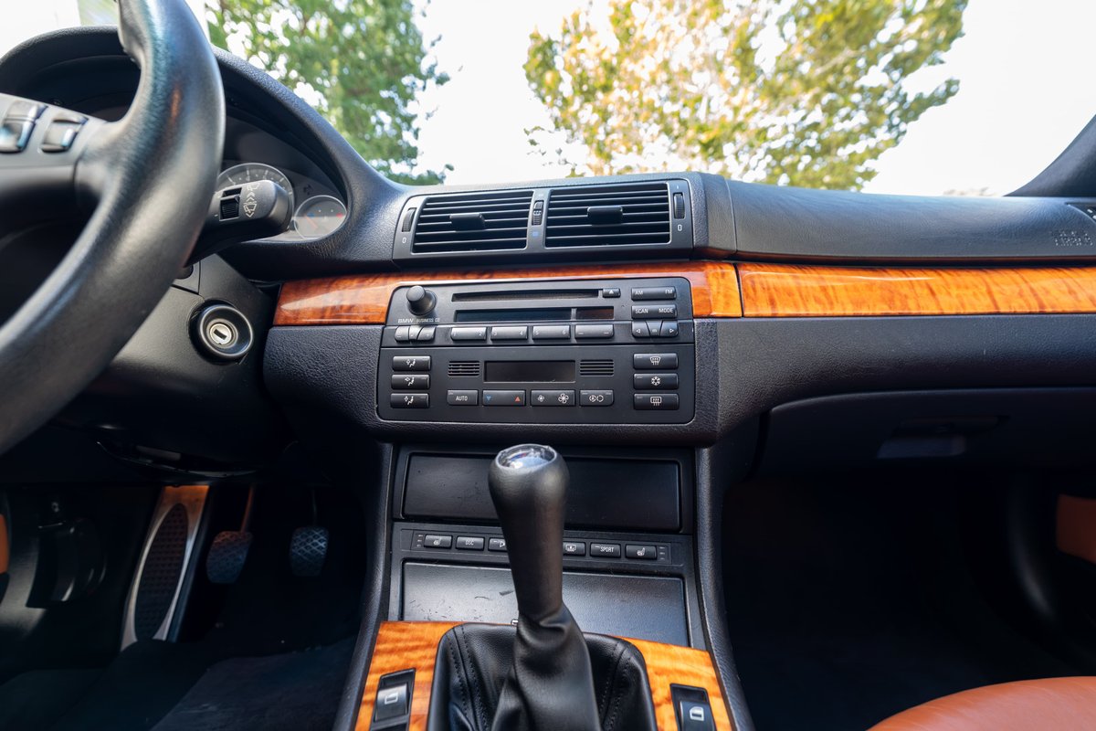 Carbon black 2002 BMW M3 interior with wood trim, manual shifter, and leather seats.