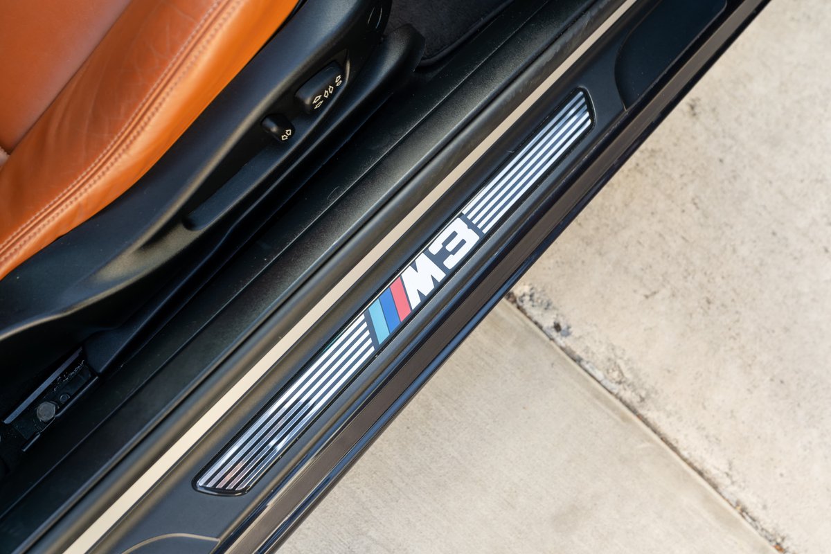 2002 BMW M3 carbon black door sill trim with M logo and tri-color stripes.