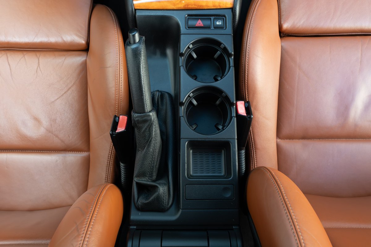 2002 BMW M3 interior: tan leather seats, center console with cup holders and parking brake.