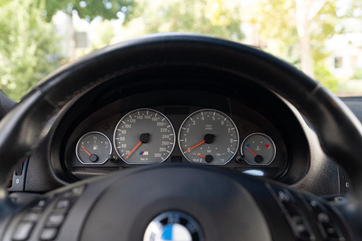 2002 BMW M3 instrument cluster with analog gauges and M logo.