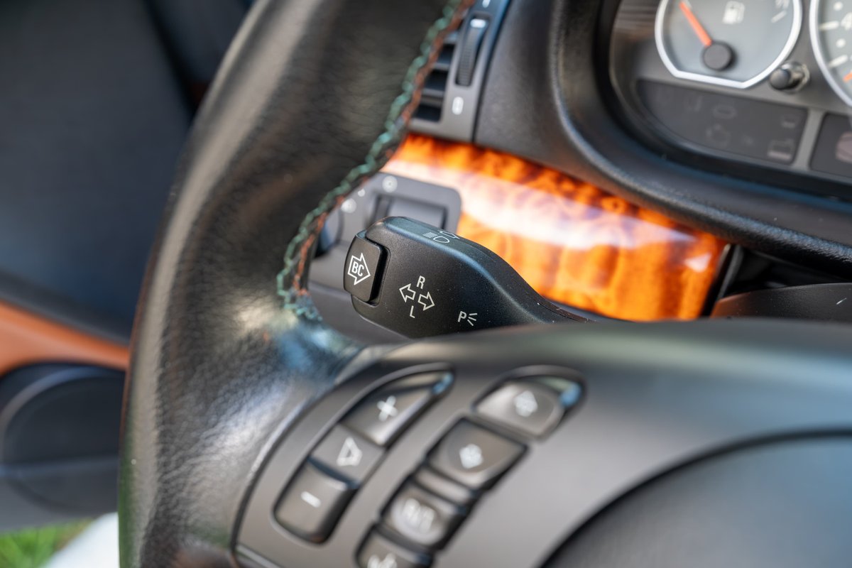 Close-up of a 2002 BMW M3 steering wheel with wood trim and turn signal stalk.