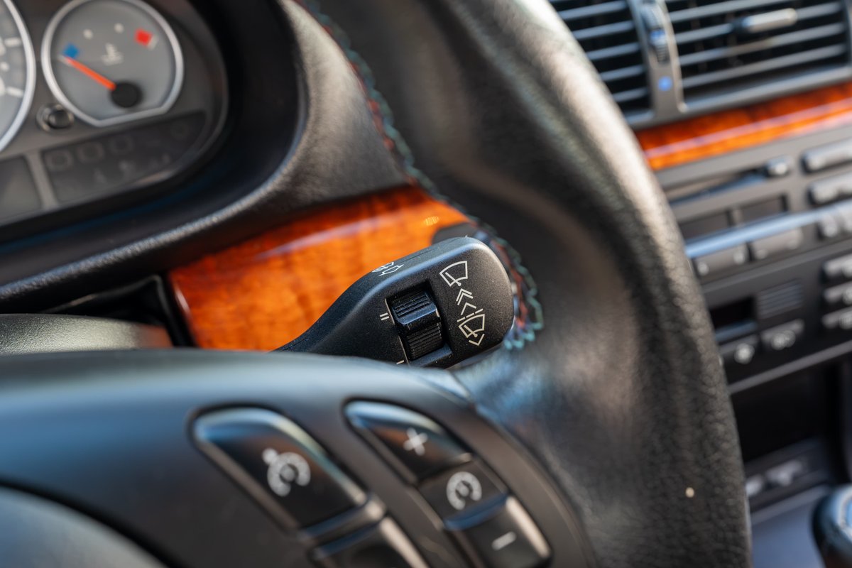 Interior shot of a 2002 BMW M3 with wood trim, showing steering wheel controls and wiper stalk.
