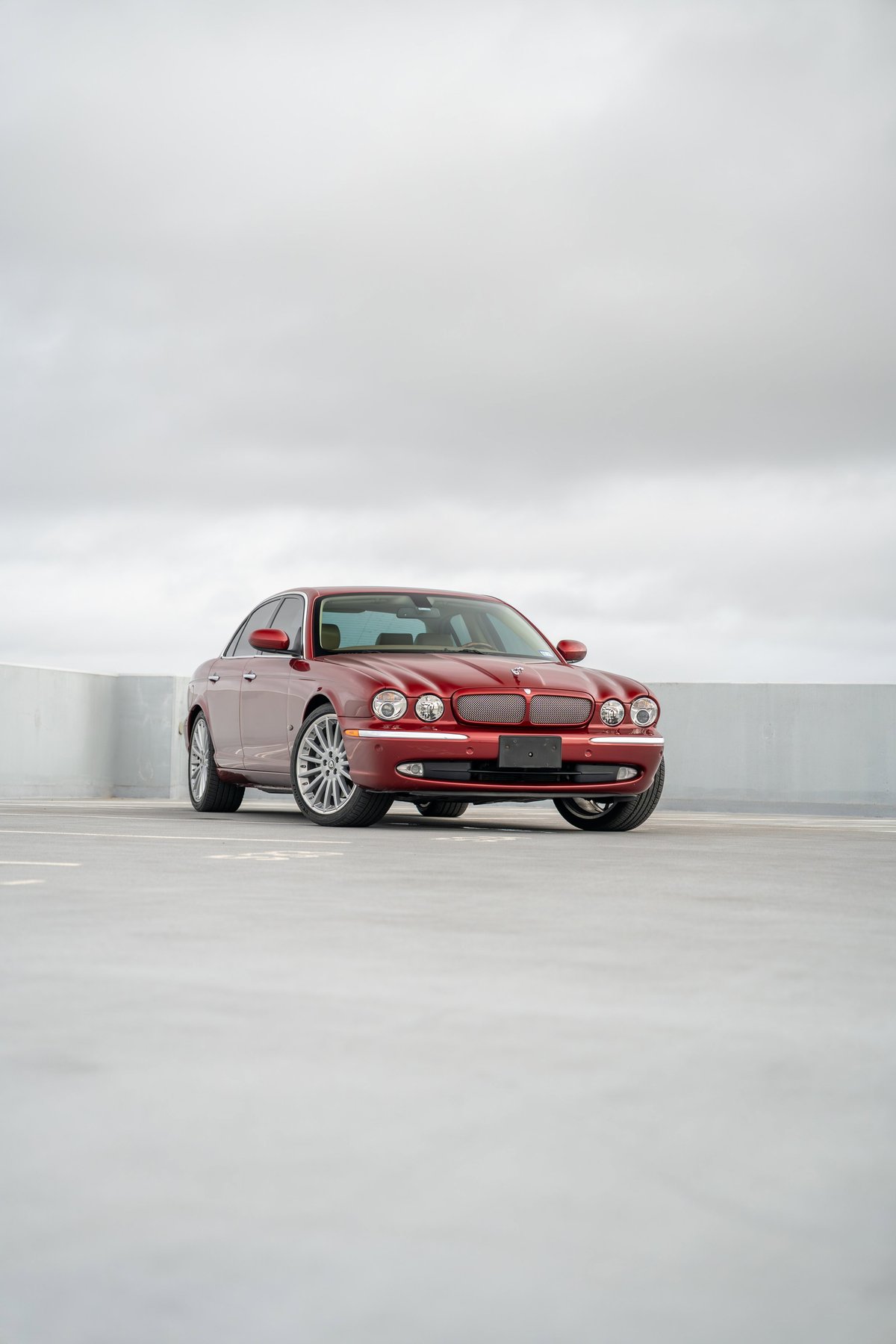 2006 Jaguar XJR in Radiance Red with chrome rims and trim, front three-quarter view.