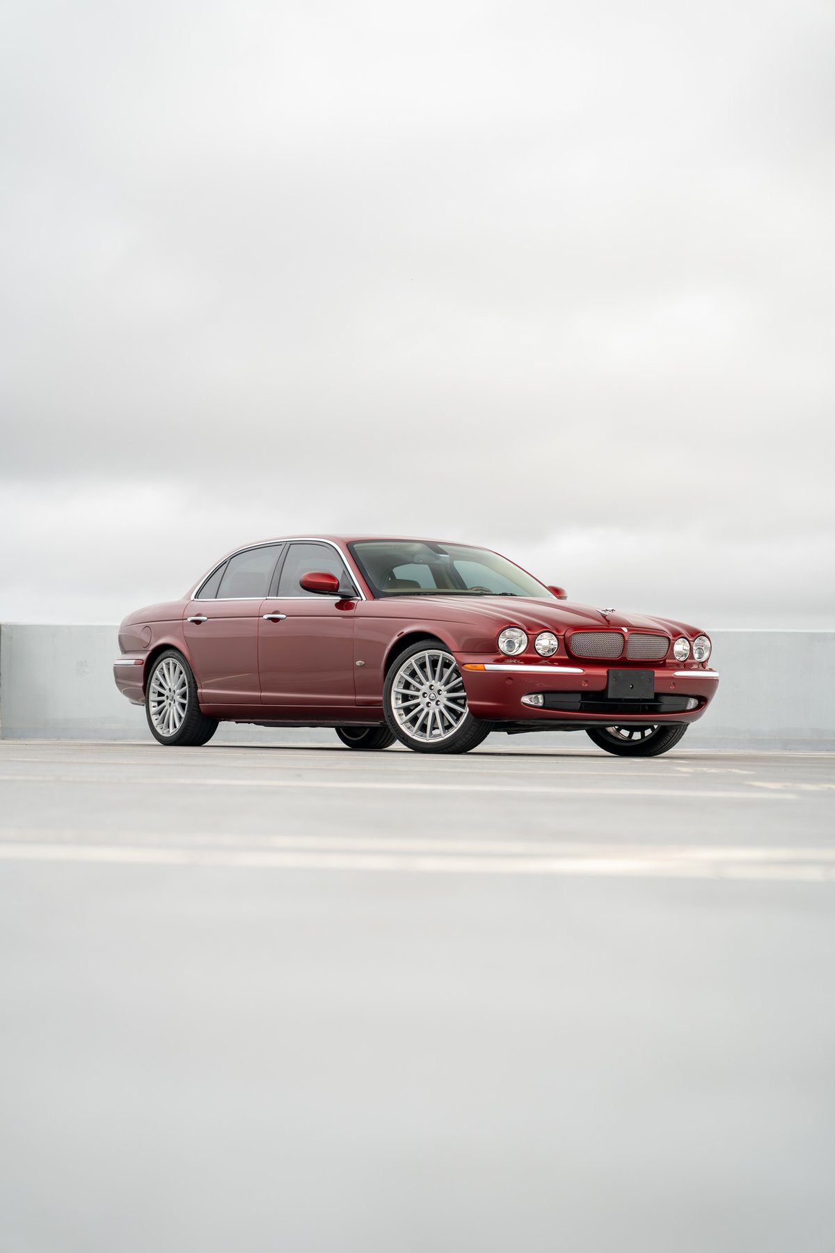 2006 Jaguar XJR in Radiance Red, showing off its multi-spoke alloy rims and chrome trim.