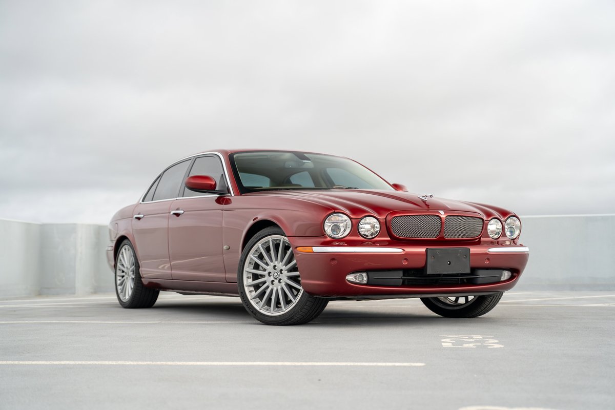 Radiant red 2006 Jaguar XJR with chrome trim and multi-spoke alloy rims.