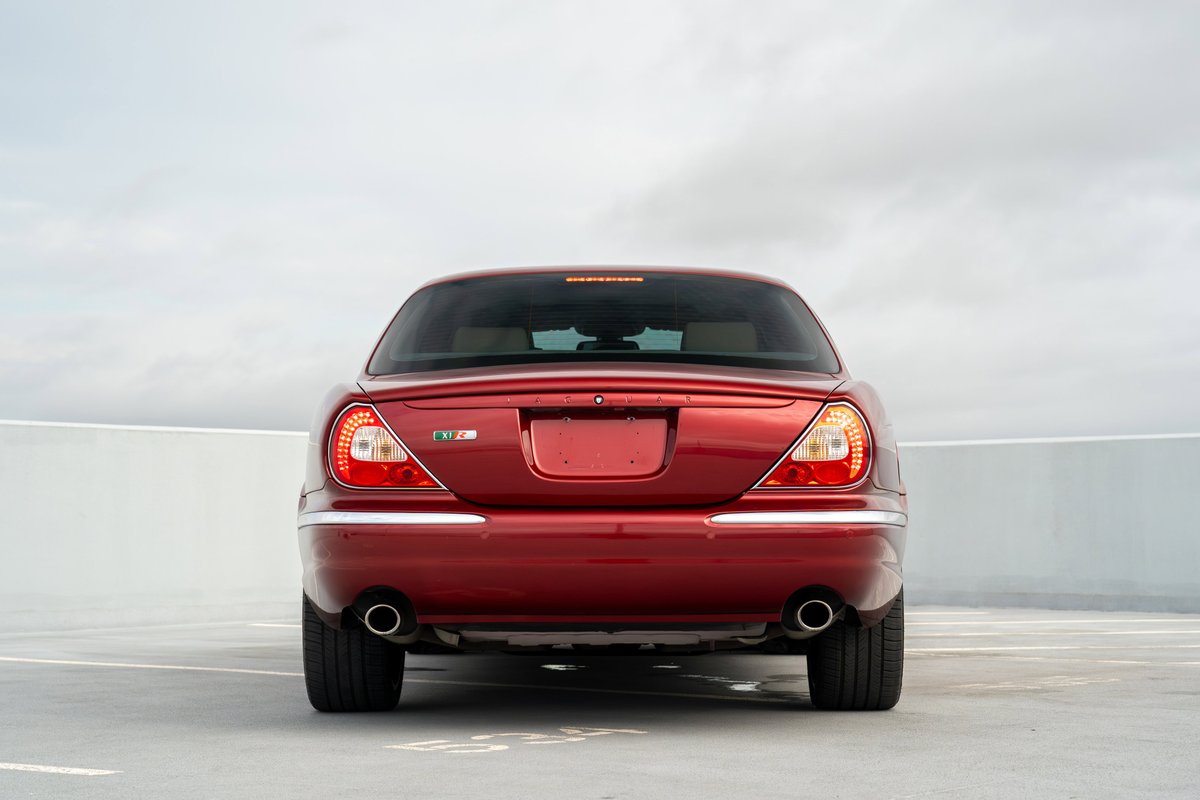 Rear view of a red 2006 Jaguar XJR with dual exhaust and chrome trim.