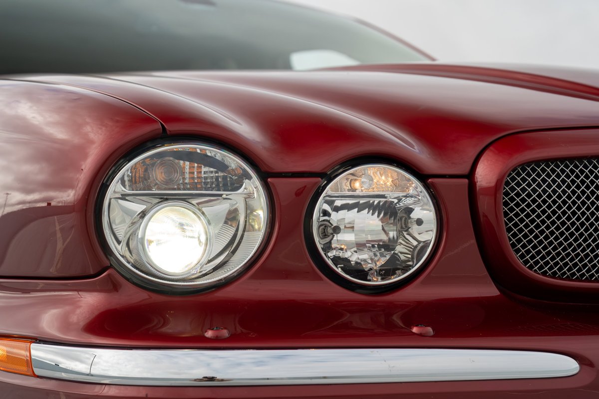 Radiance Red 2006 Jaguar XJR headlights and chrome grille detail.