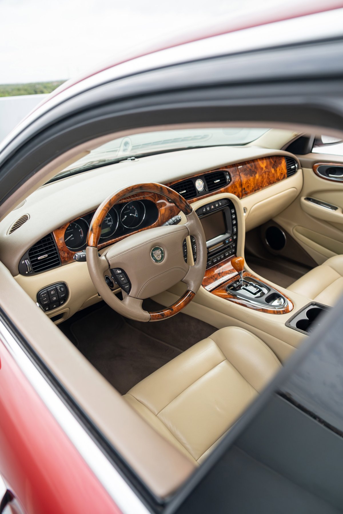 Radiance Red 2006 Jaguar XJR interior features wood trim and tan leather seats.