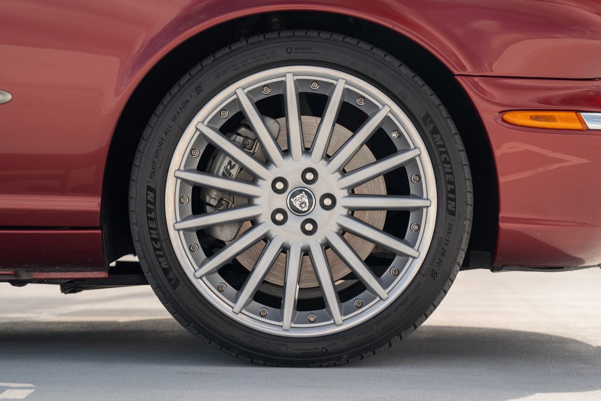 Close up of a red 2006 Jaguar XJR with a multi-spoke alloy rim and Michelin tire.