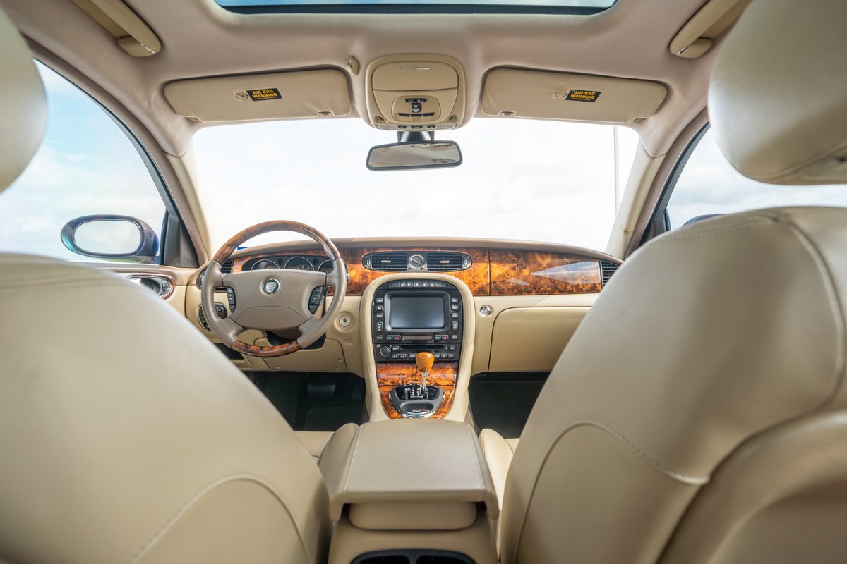 2006 Jaguar XJR interior: Tan leather seats, wood trim, infotainment screen.