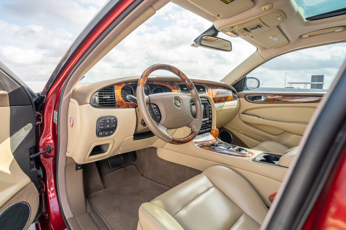 Radiance Red 2006 Jaguar XJR interior: tan leather seats, wood trim dashboard, steering wheel.