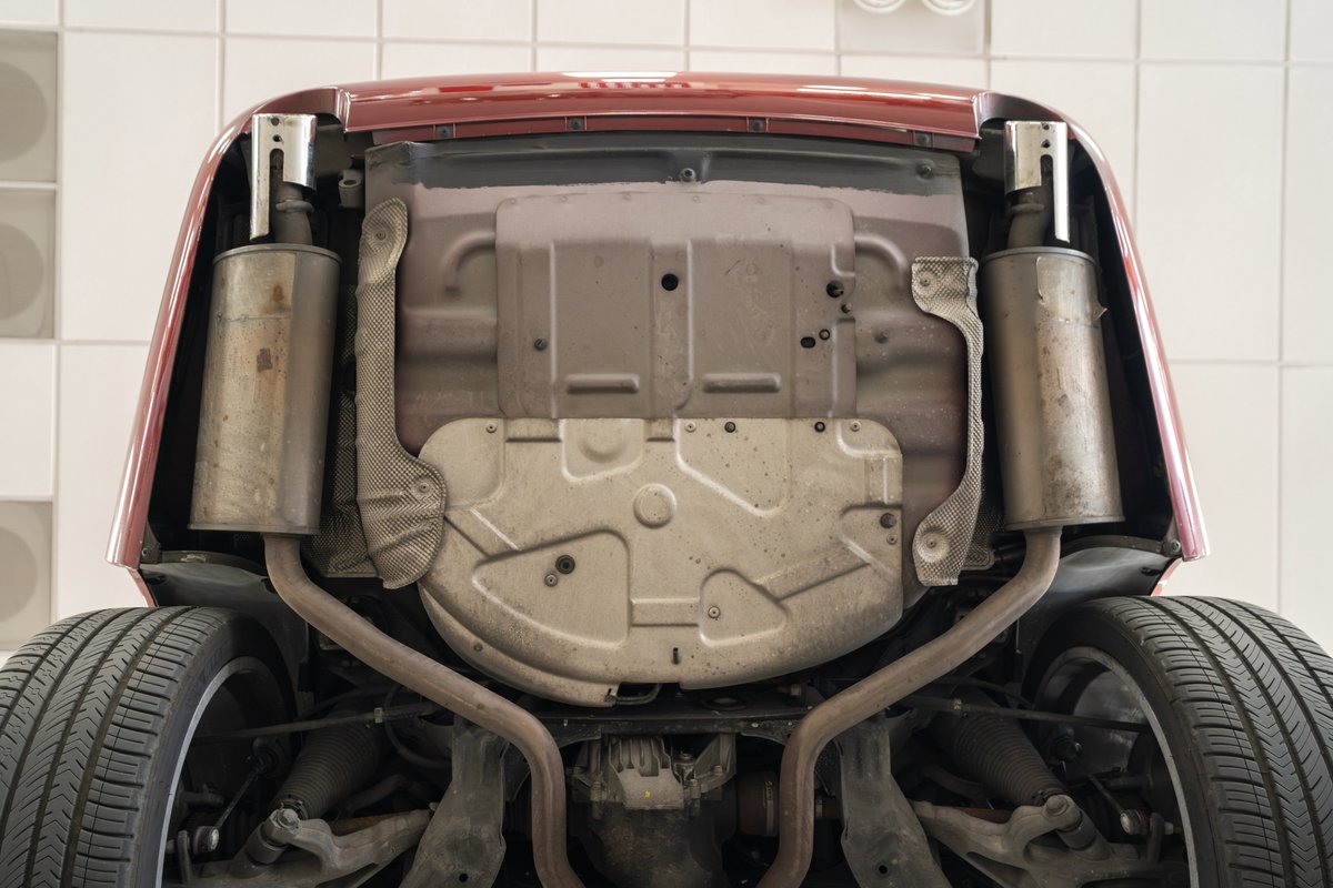 Underside view of a red 2006 Jaguar XJR showing dual exhaust and suspension components.