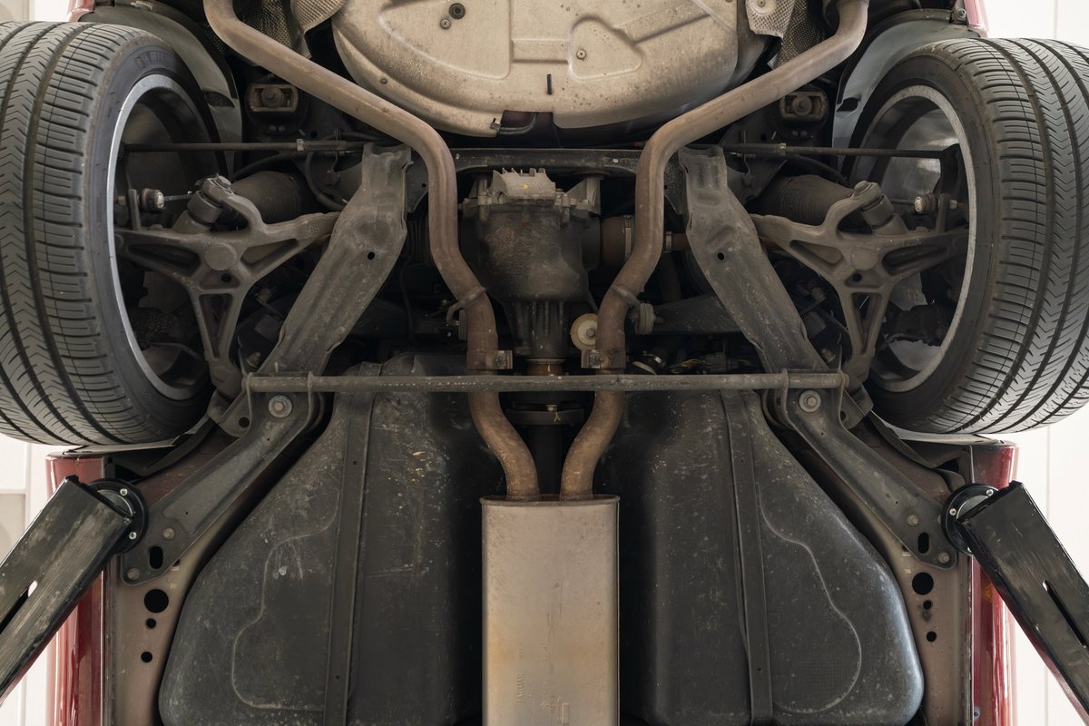 Underneath view of a 2006 Jaguar XJR in Radiance Red, showing rear suspension, exhaust, and rims.