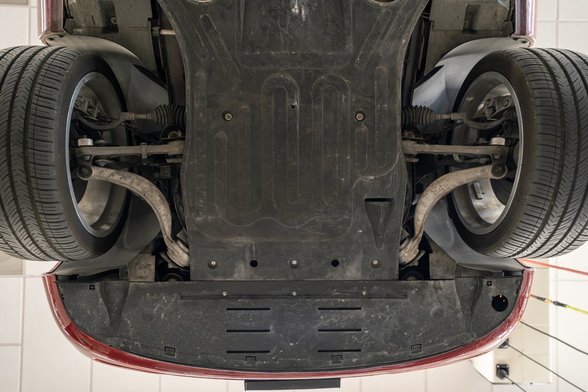 Underside view of a 2006 Jaguar XJR in Radiance Red, showing suspension and underbody trim.