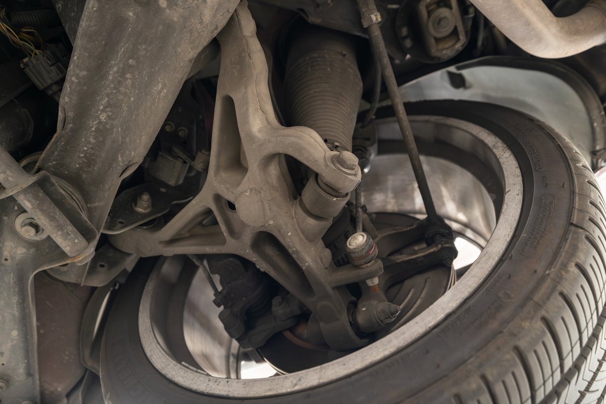 Underside view of a 2006 Jaguar XJR showing air suspension, control arms, and front wheel with alloy rim.