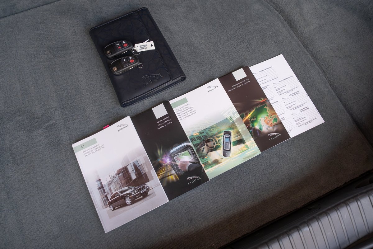 Jaguar XJR owner's manual, service book and keys on gray seat.