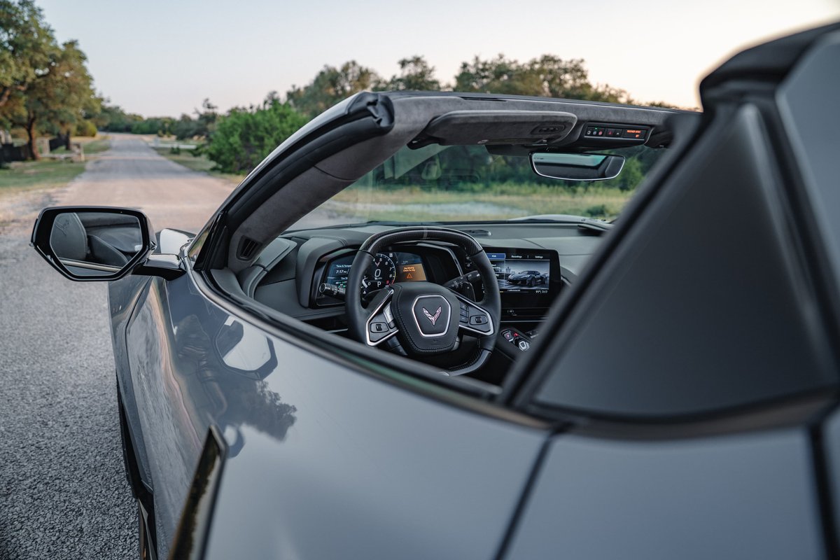 Gray 2025 Chevrolet Corvette Z06 convertible interior and side mirror, parked on a road.