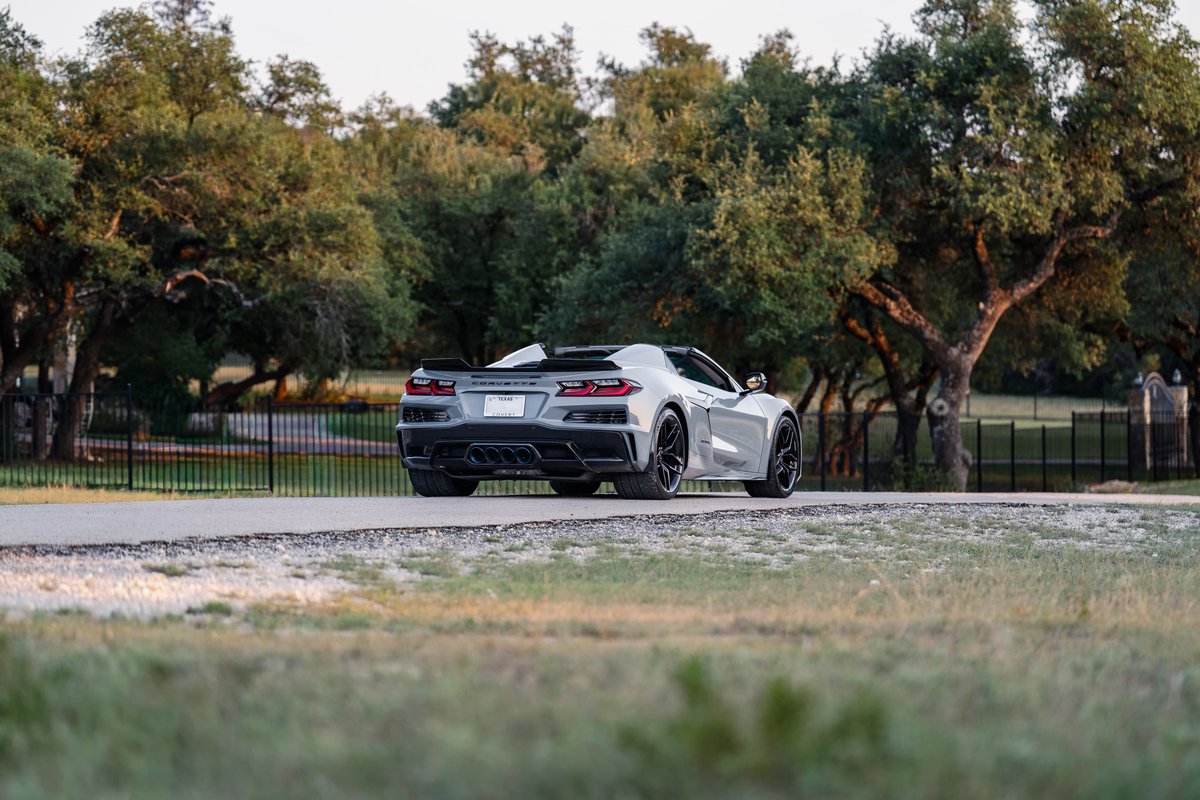 2025 Chevrolet Corvette Z06 in Sea Wolf Gray, rear view, showing black rims and exhaust tips.