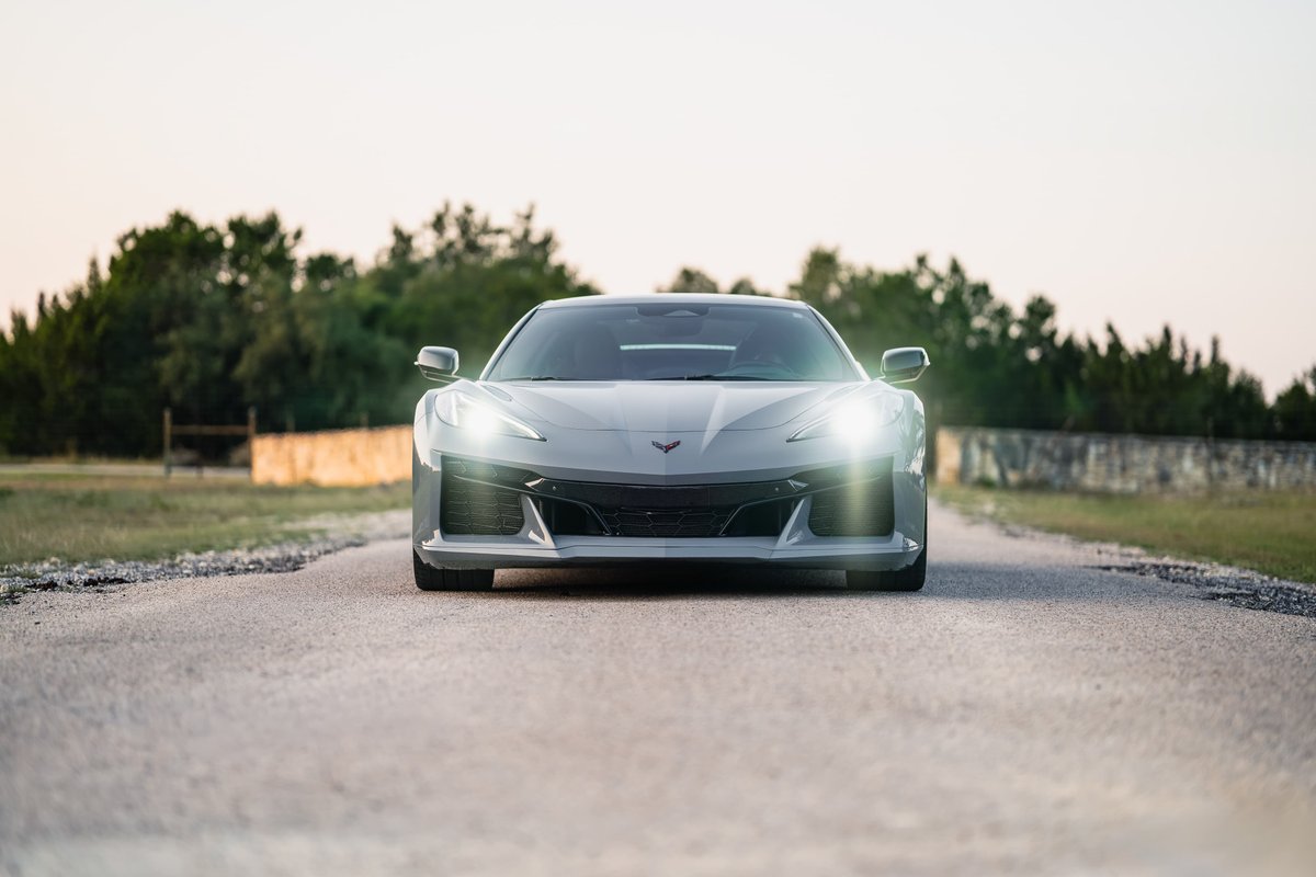 Front view of a Sea Wolf Gray 2025 Chevrolet Corvette Z06, with headlights illuminated.