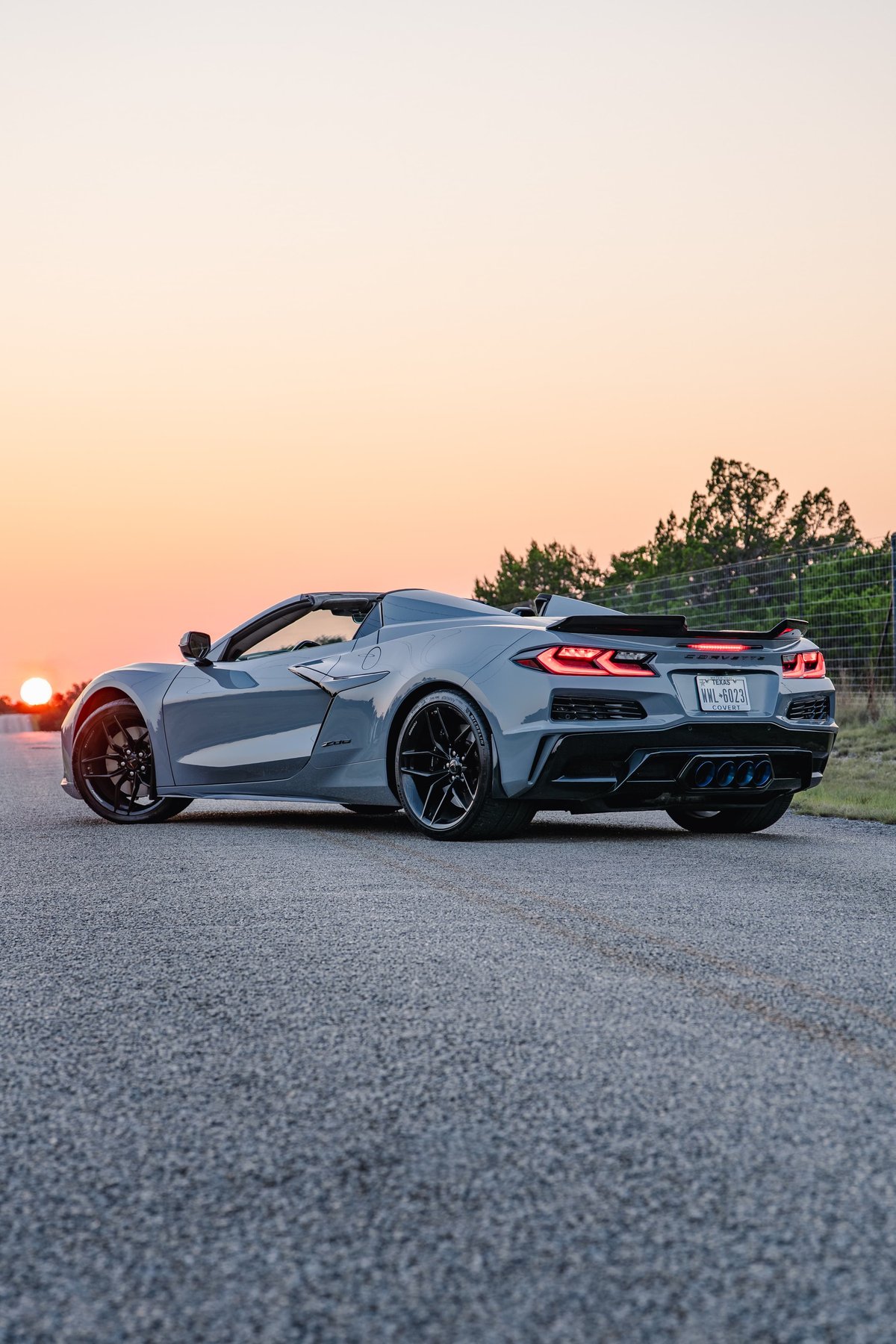 2025 Chevrolet Corvette Z06 in Sea Wolf Gray, rear 3/4 view, black rims, spoiler.