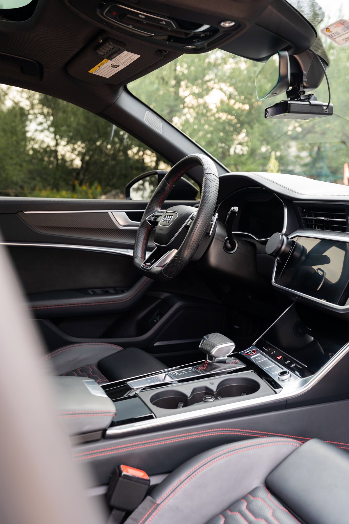 Interior of a 2022 Audi RS6 in Nardo Grey, with red stitching, carbon fiber trim, and a touchscreen.