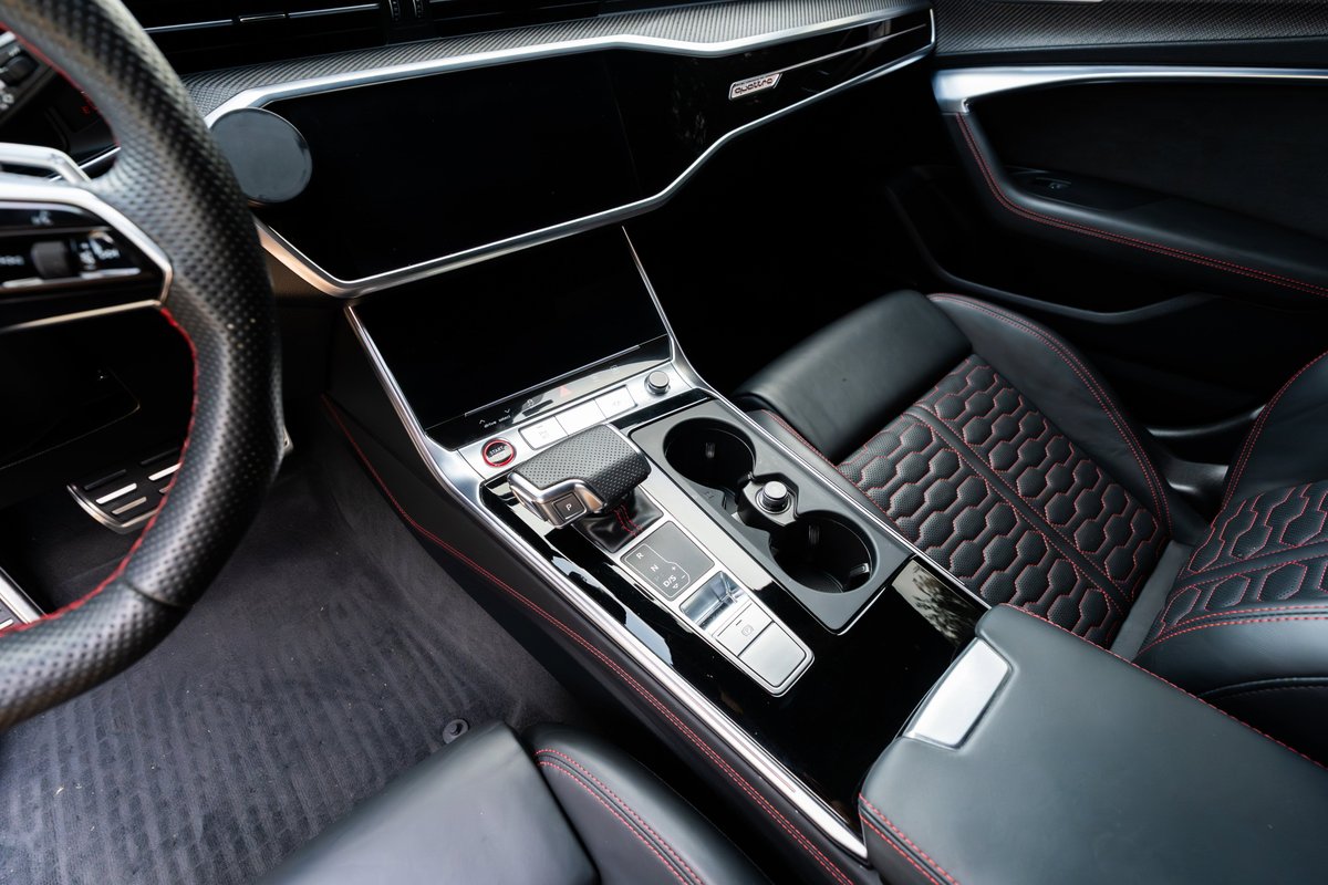 Interior shot of a 2022 Audi RS6 with Nardo Grey exterior, black leather, red stitching, and carbon fiber trim.