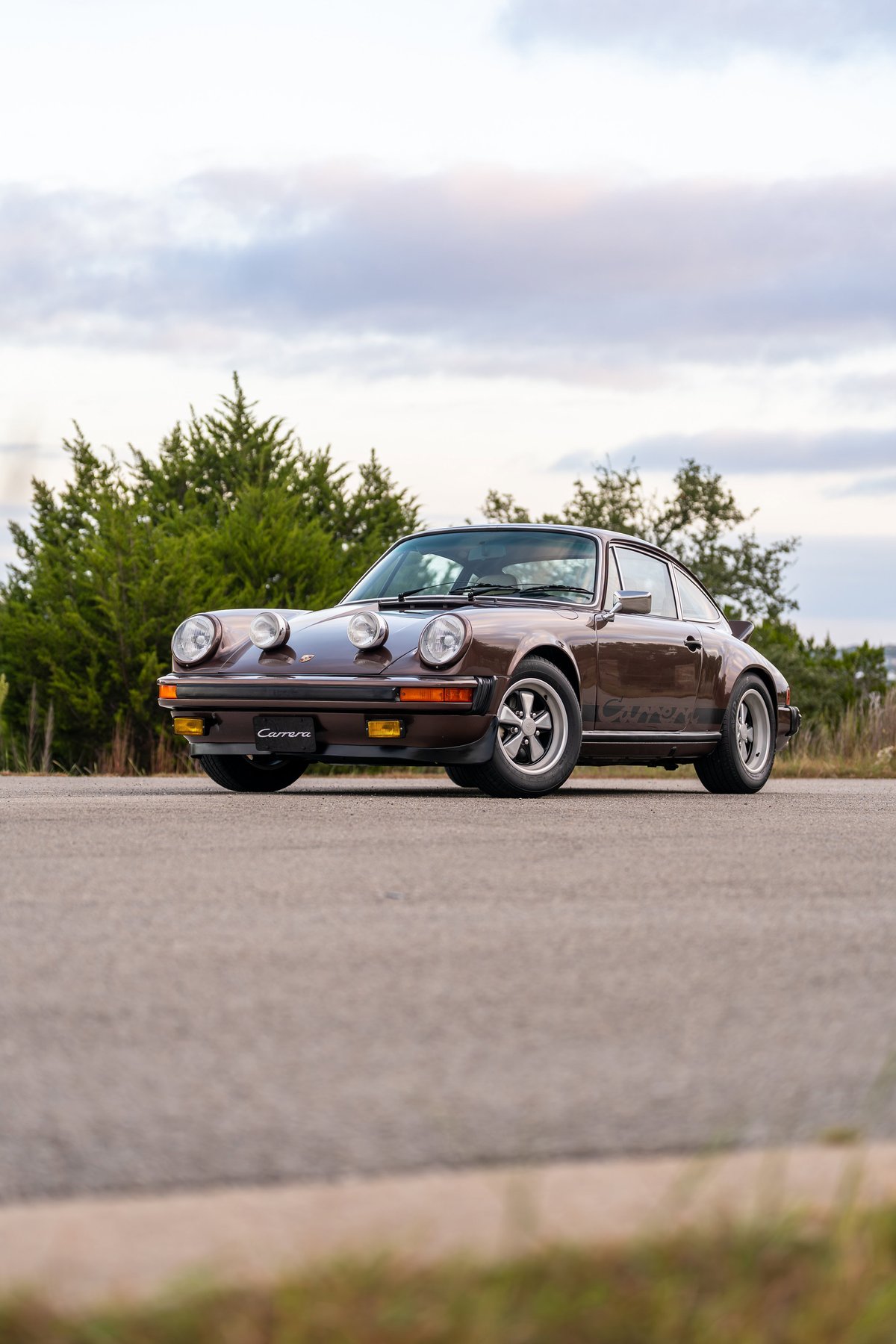 Brown metallic 1975 Porsche 911 Carrera with Fuchs rims and black Carrera livery.