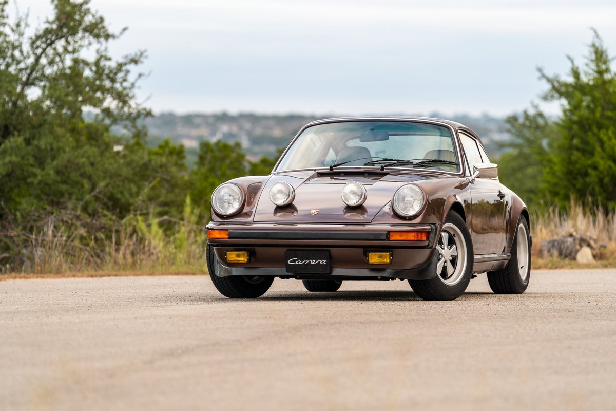 Front view of a copper brown metallic 1975 Porsche 911 Carrera with classic Fuchs rims.