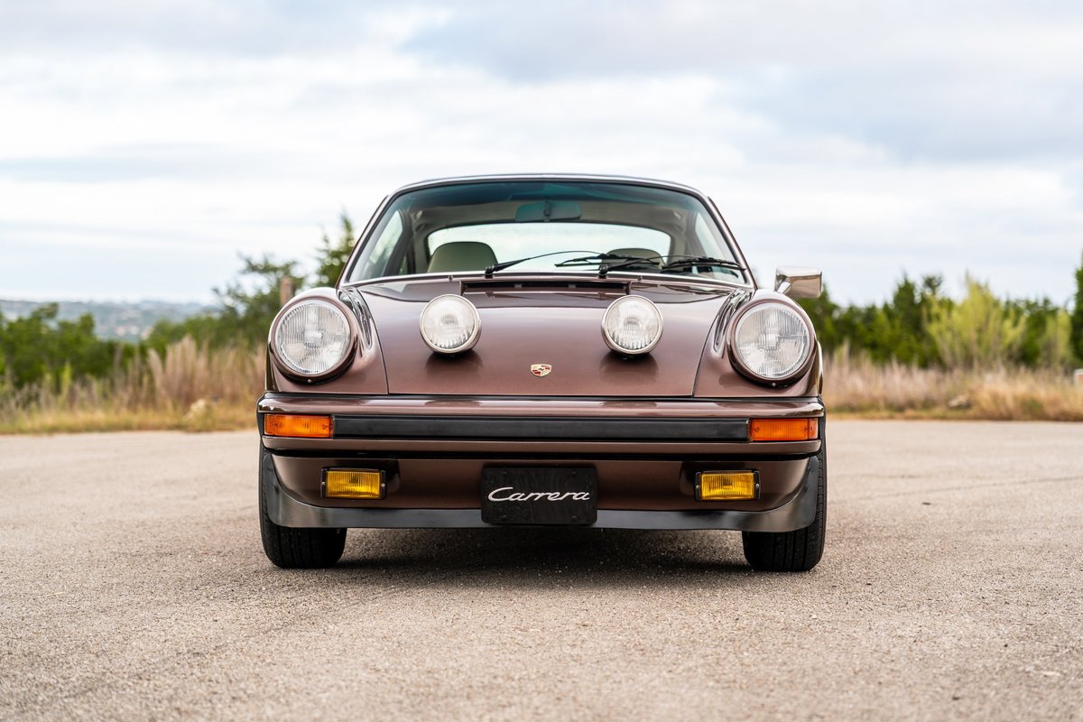 Front view of a copper brown metallic 1975 Porsche 911 Carrera with rally lights.