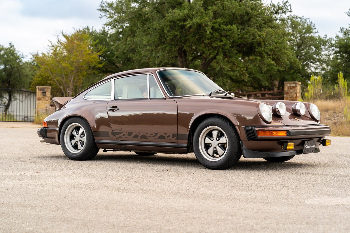 A brown 1975 Porsche 911 Carrera in copper brown metallic, with Fuchs rims and Carrera livery.