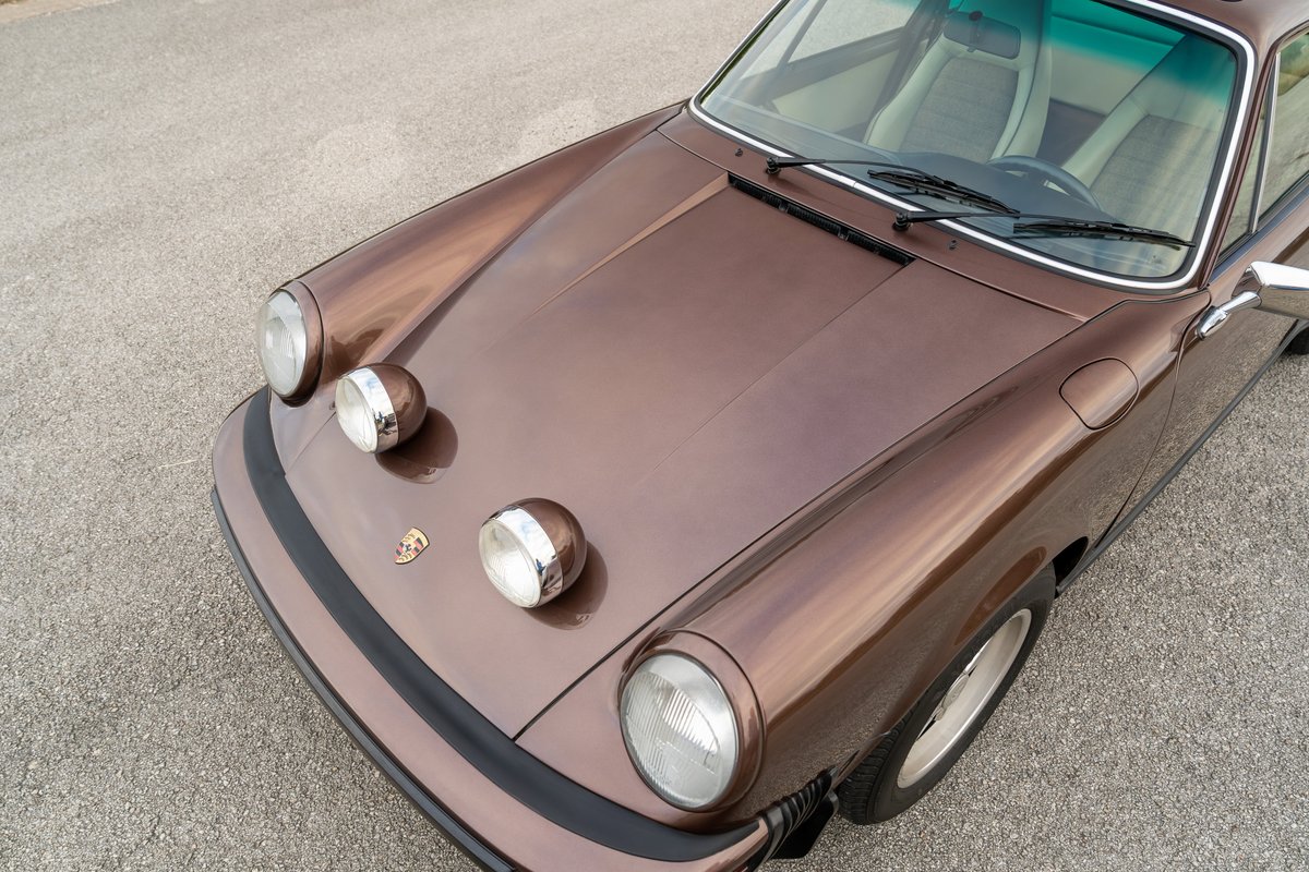 Front view of a copper brown metallic 1975 Porsche 911 Carrera with fog lights.