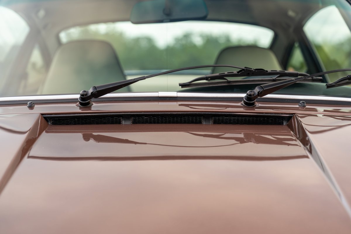 Close-up of a copper brown 1975 Porsche 911 Carrera hood with wipers and vent.
