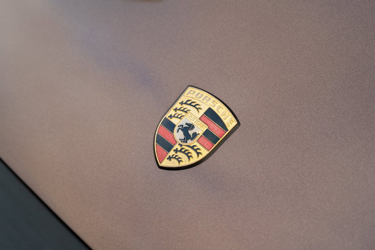 Porsche crest badge on the hood of a copper brown metallic 1975 Porsche 911 Carrera.