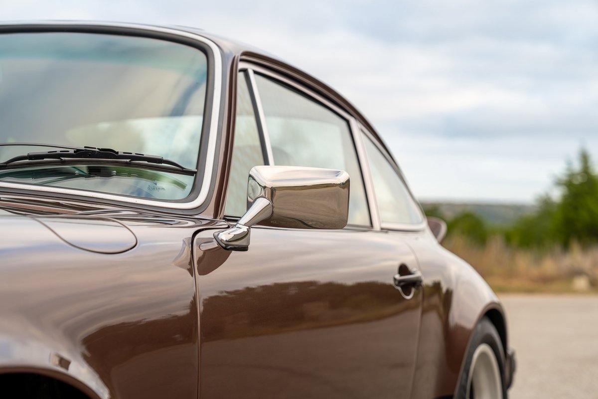 Brown metallic 1975 Porsche 911 Carrera detail shot, showing chrome trim and side mirror.