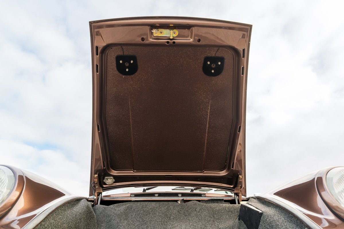 Open hood of a copper brown metallic 1975 Porsche 911 Carrera showing the front trunk lining.