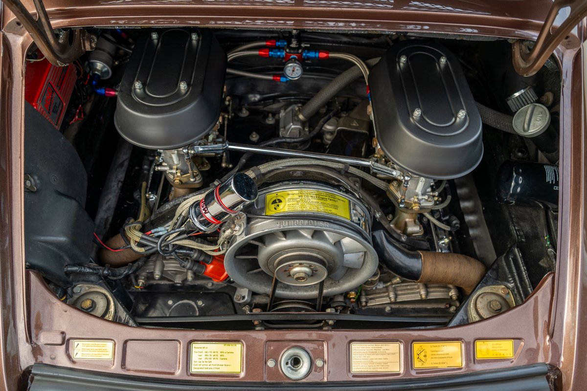 Close-up of a vintage copper brown metallic 1975 Porsche 911 Carrera engine bay. Twin Weber carburetors, fan shroud.