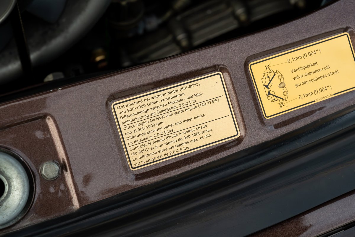 Porsche 911 Carrera engine bay features service decals detailing oil level and valve clearance.
