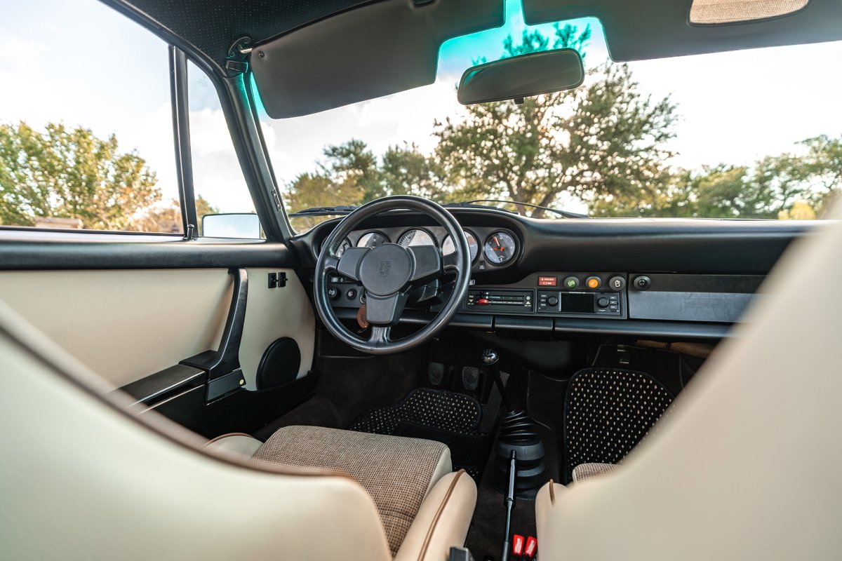 1975 Porsche 911 Carrera interior, tan door panel, black dash, four-spoke steering wheel.