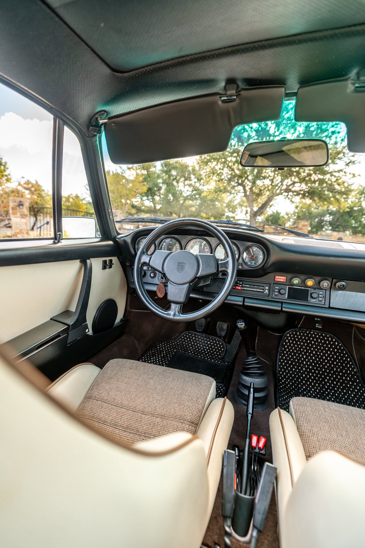 1975 Porsche 911 Carrera interior: tan leather, cloth seats, black carpet mats, manual shifter.