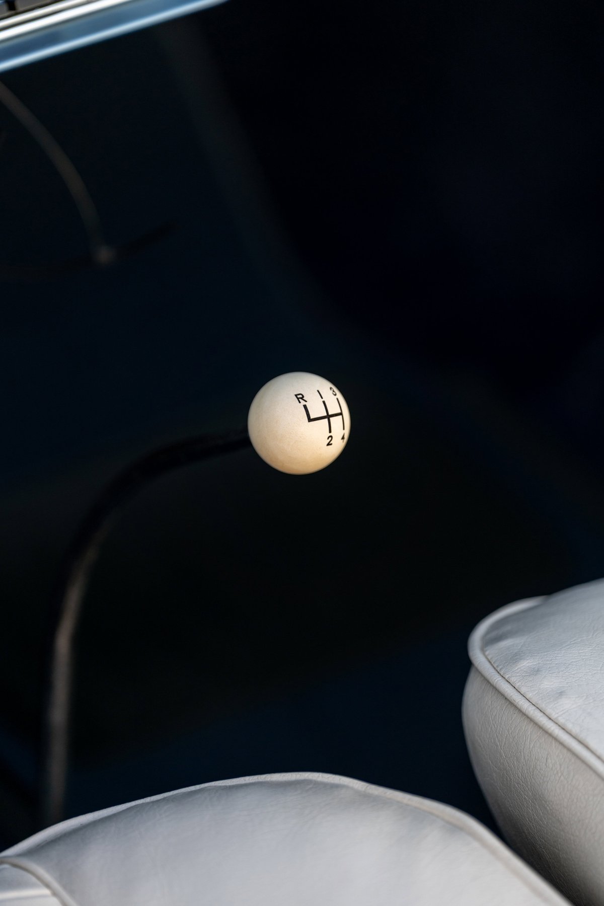 Classic white 4-speed manual shifter knob in a blue 1966 Chevrolet Corvair convertible interior.