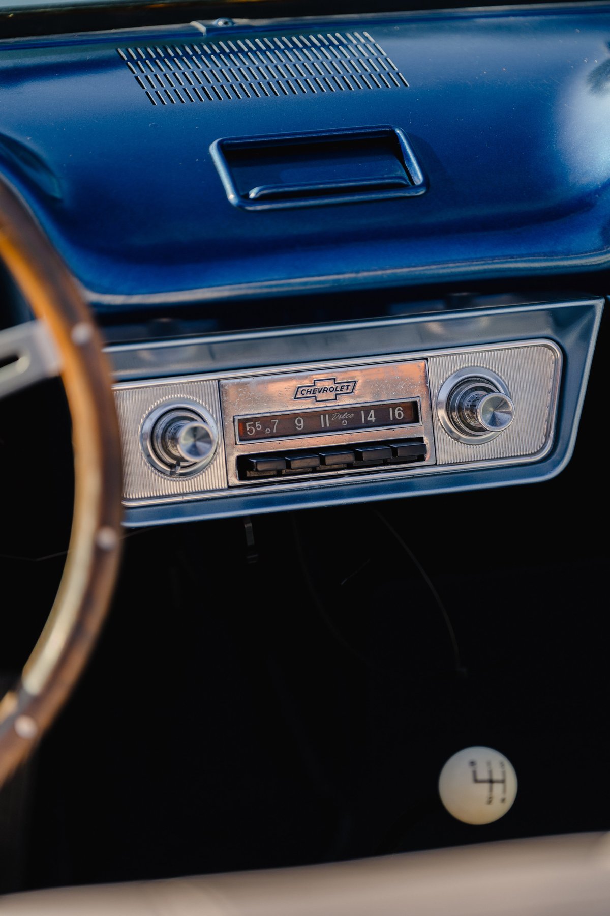 1966 Chevrolet Corvair convertible's vintage dashboard with a chrome radio and wooden steering wheel.