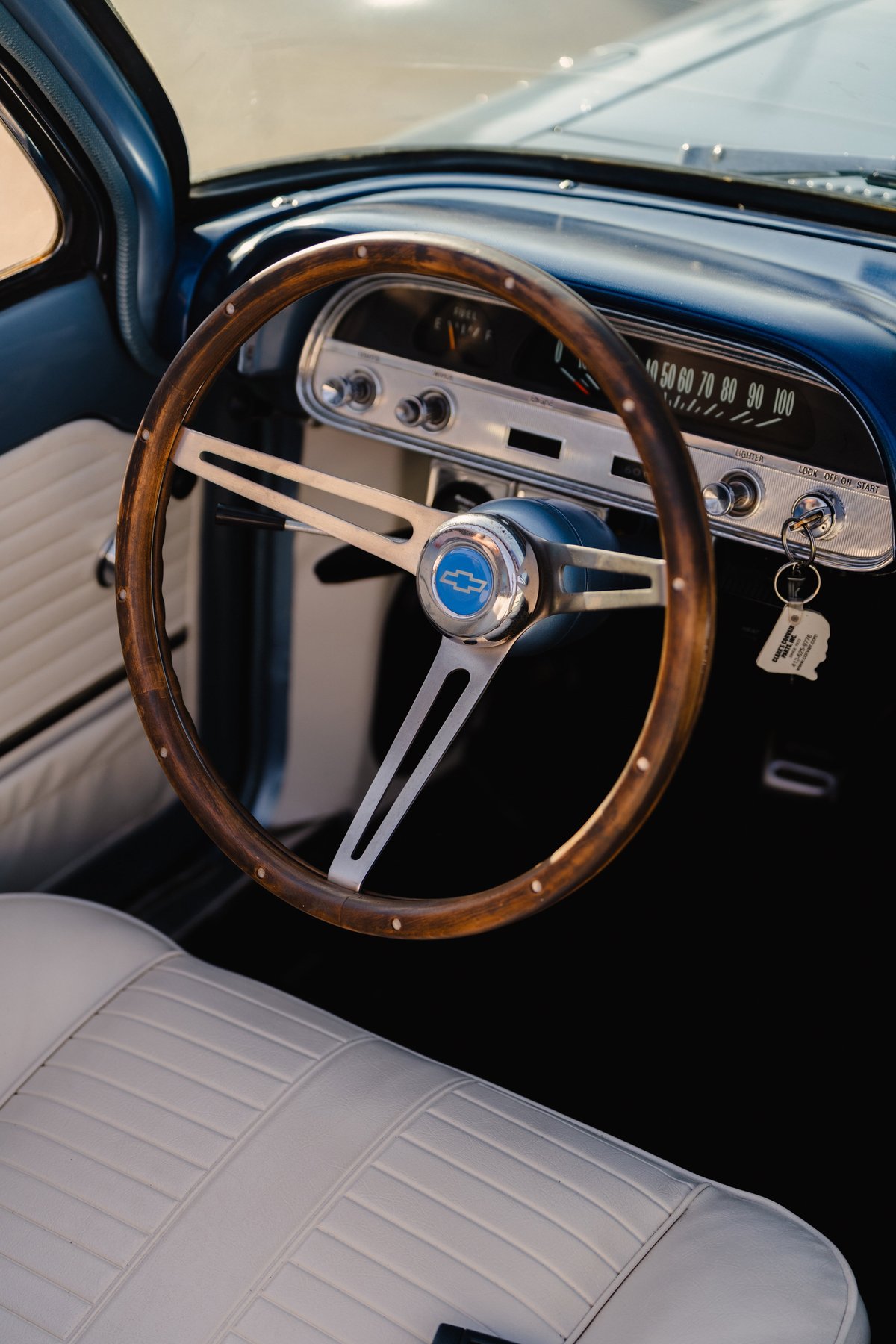 Close-up of a 1966 Chevrolet Corvair convertible's vintage wood-rimmed steering wheel and dashboard.