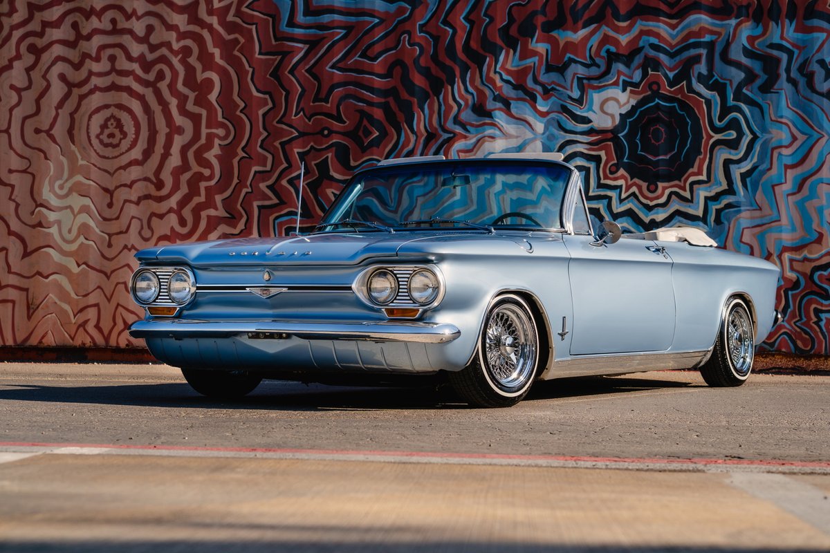 1966 blue metallic Chevrolet Corvair convertible with chrome wire wheels and whitewall tires.