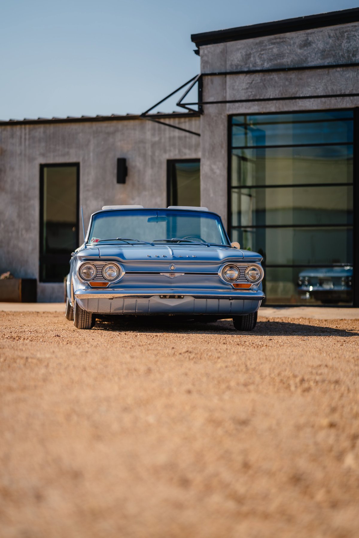 Front view of a blue metallic 1966 Chevrolet Corvair convertible with chrome trim.