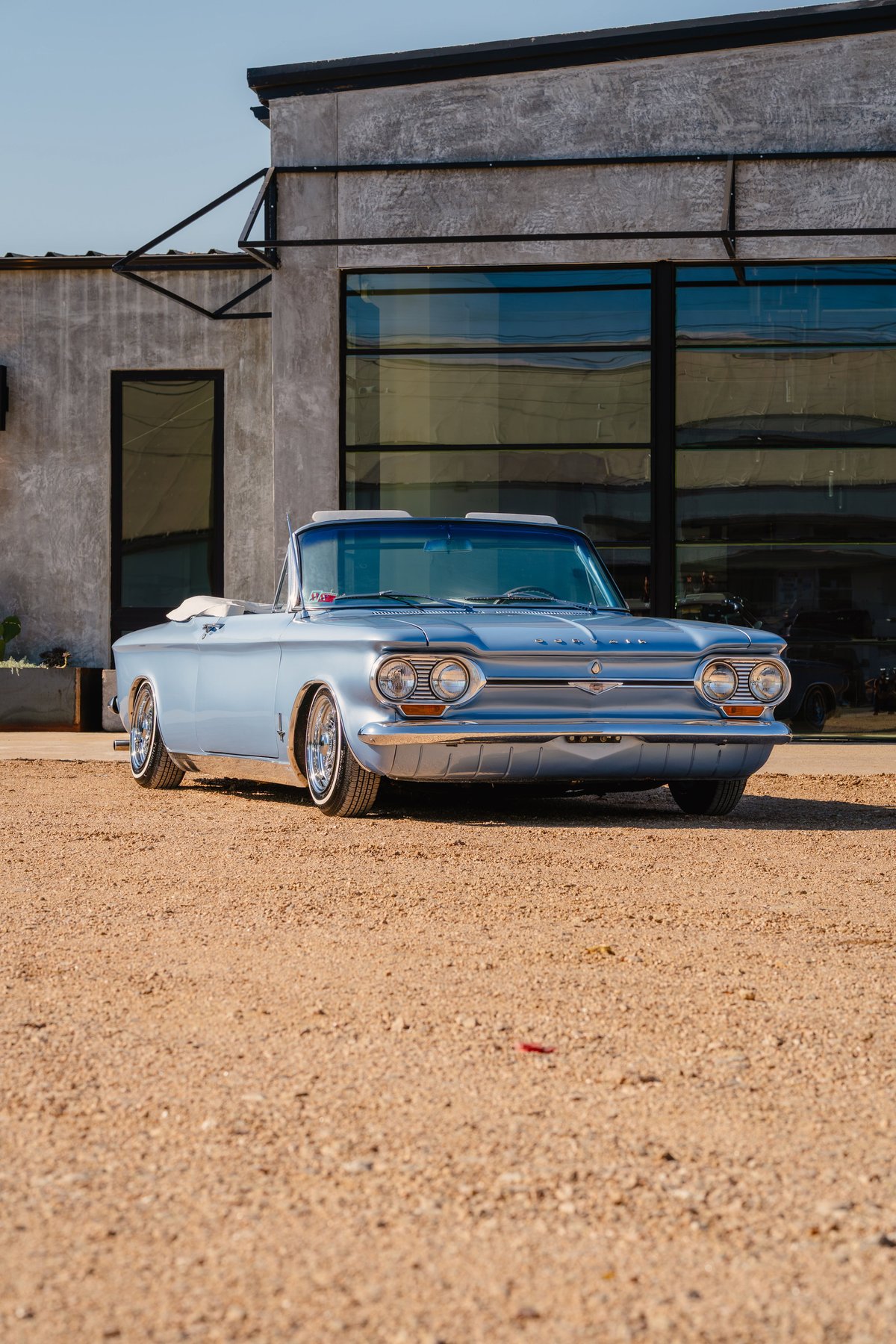 1966 blue metallic Chevrolet Corvair convertible with chrome rims and side trim.