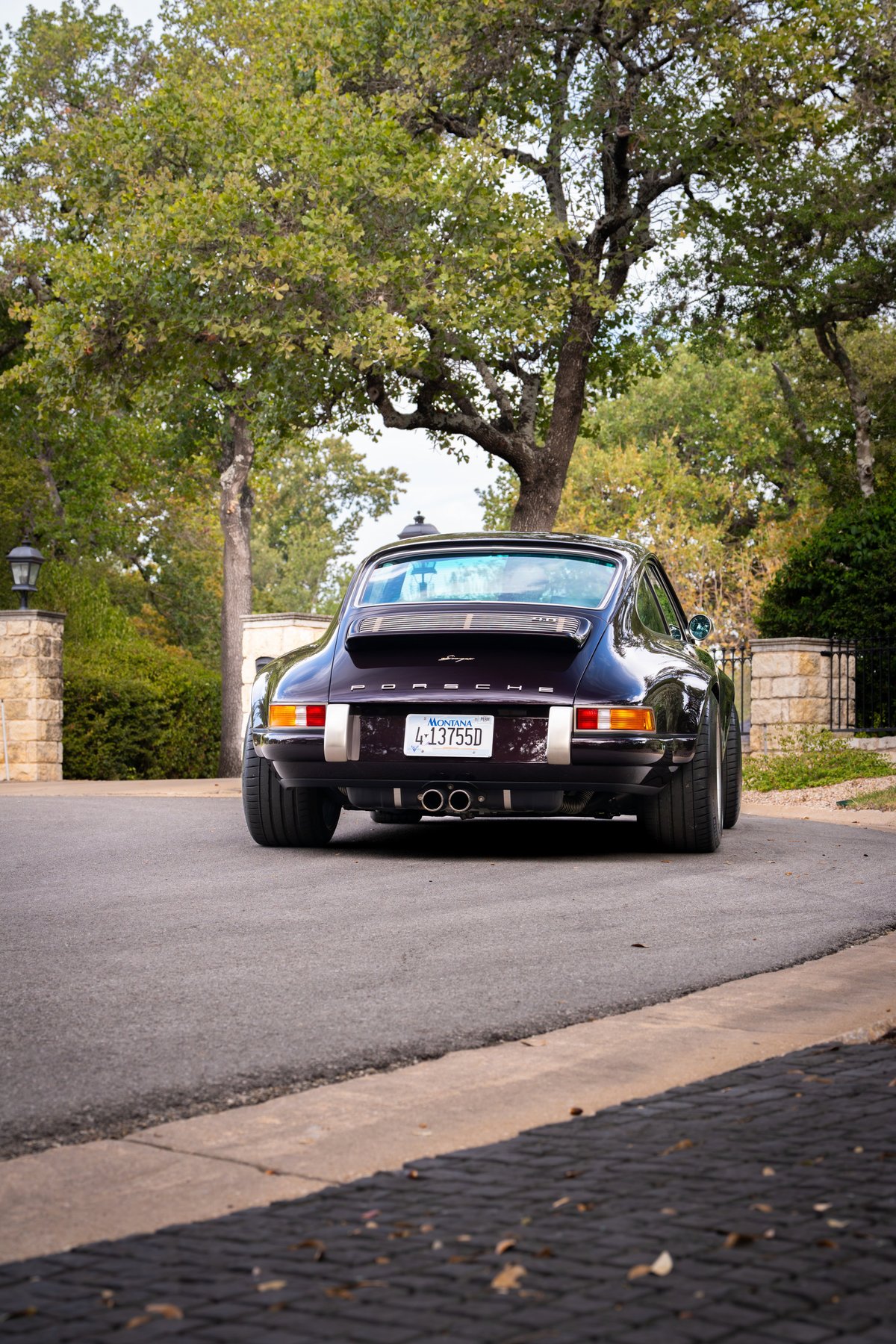 Aubergine metallic 1990 Singer Porsche 911 rear view, showing chrome exhaust tips and Fuchs rims.