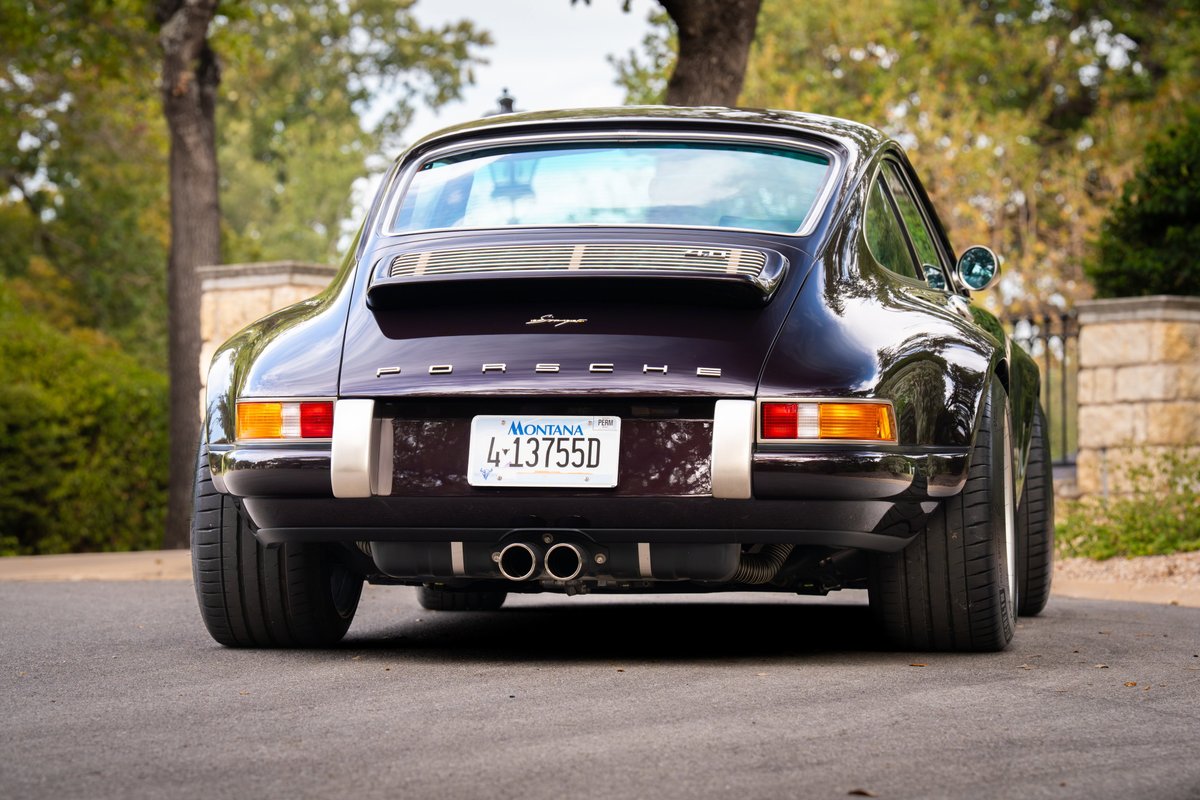 Rear view of an aubergine metallic 1990 Singer 911 with polished exhaust tips and wide wheels.