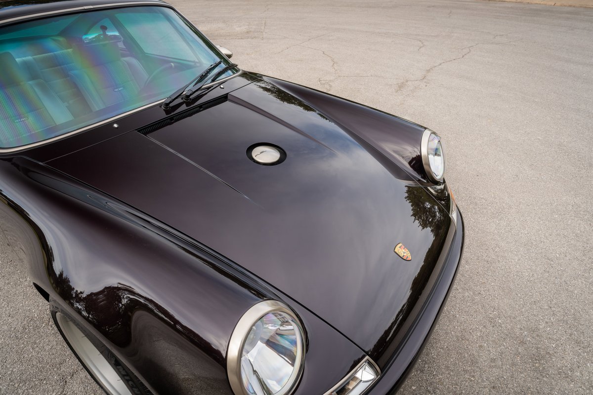 Aubergine metallic 1990 Singer Porsche 911 front quarter view with chrome headlight trim.